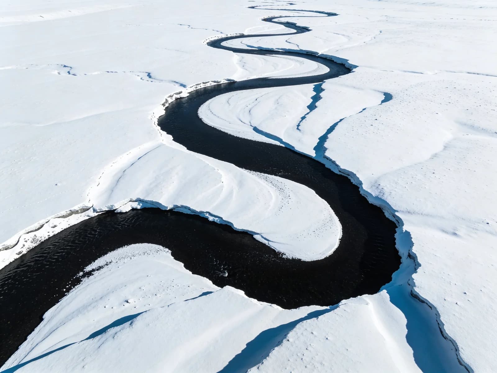 Mäandernder Fluss durch verschneite Tundra